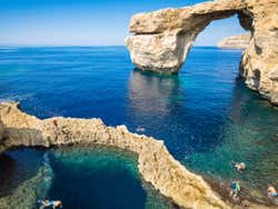Rock formations in the sea with people swimming in natural pools