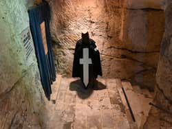A cloaked figure with a cross in front of it