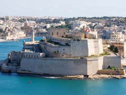 A stone fort surrounded by water with a city in the distance