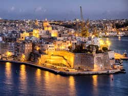 A port lit up at night time under an evening sky