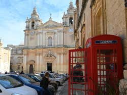 A red phone box with a cathedral seen behind it
