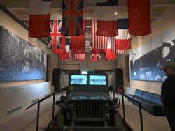 A man standing beside an old jeep in the war museum