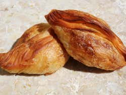 Two pastizzi on a marble table