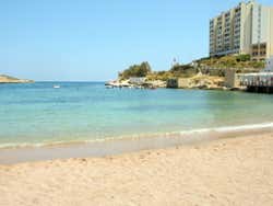 A sandy beach with waves crashing on the shore under a blue sky