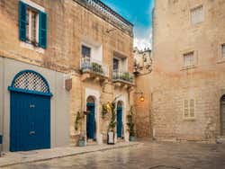 A courtyard with blue doors and balconies with white railings