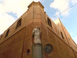 A white statue at the corner of a building under a blue sky