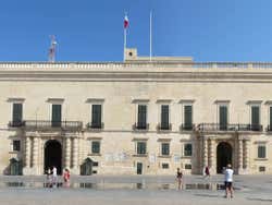 A long building with people walking past it under a blue sky